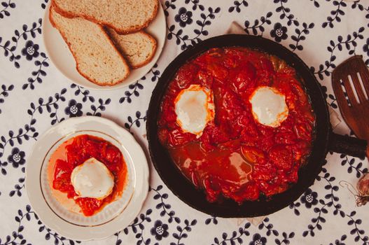 Pan shakshuka met eieren, feta en verse kruiden geserveerd met brood