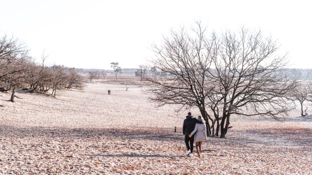Stel geniet van een romantische wandeling langs het water in Boxmeer tijdens zonsondergang